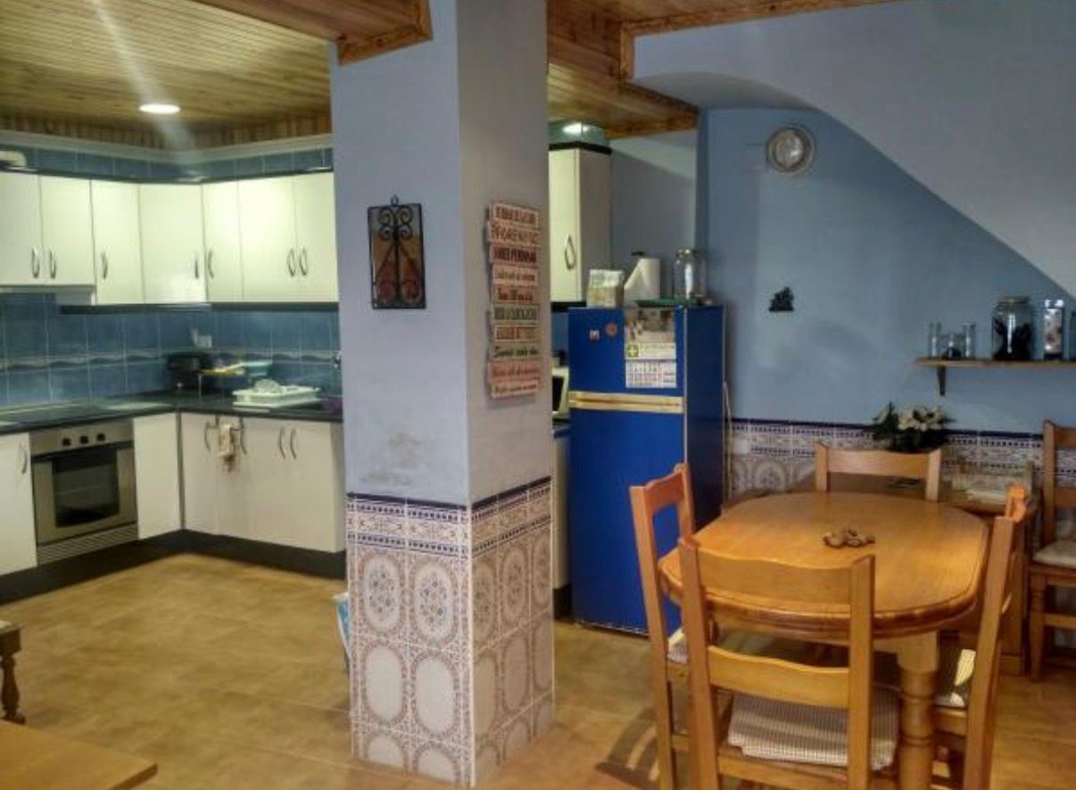 Cocina abierta al comedor con mesa y nevera