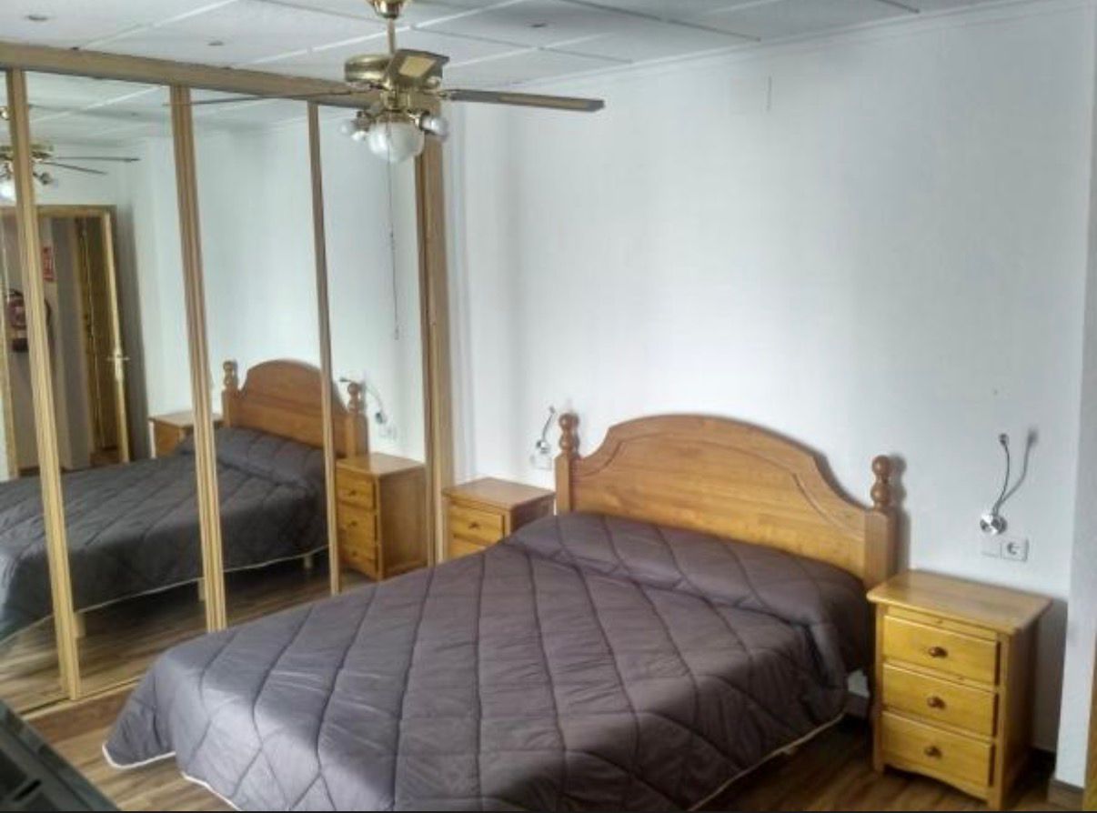 Dormitorio con cama de matrimonio, armario y ventilador de techo